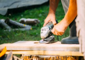 Man performs carpentry work outdoors.