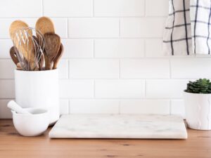 Stylish white kitchen background with kitchen utensils standing on wood countertop